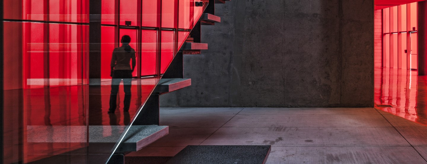 Red-lit modern office with a staircase and a reflected figure, signaling a bold, forward-looking CIB brand.
