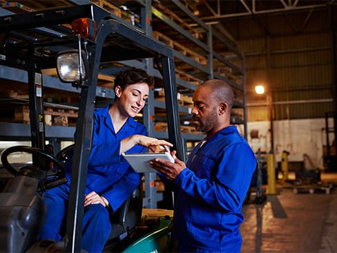Two people discussing plans in a warehouse